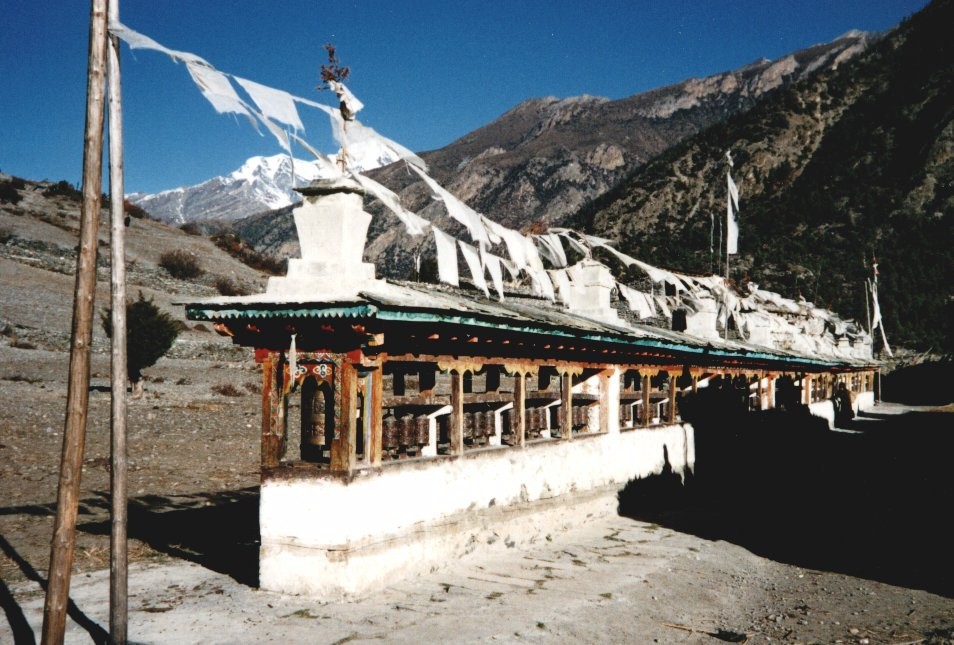 Mani Wall ( Buddhist shrine ) with Prayer Flags and Prayer Wheels