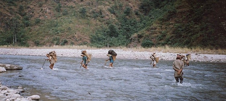 Porters fording the Piluwa Khola on route up the Arun Valley to Mount Makalu base camp